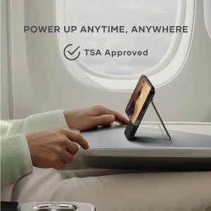 Satechi OntheGo Qi2 magnetisk powerbank med stativ, som holder en telefon oppreist på et flybord