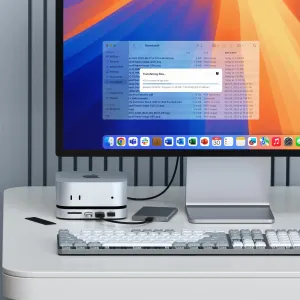 Satechi Mac Mini M4 Stand & Hub med SSD-kabinet på et skrivebord under en skærm, med porte foran og kabel.