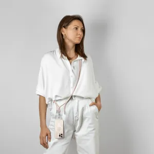 Satechi OntheGo USB-C-nøkkelbåndkabel i Desert Rose, båret på tvers av kroppen med en smarttelefon festet ved midjen.