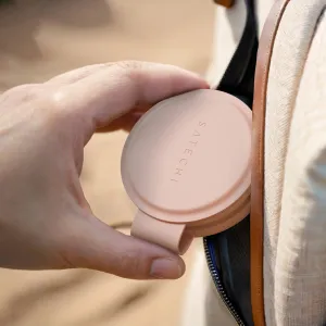 Satechi OntheGo vikbar trådlös Qi2-laddare i Desert Rose hålls bredvid en resväska