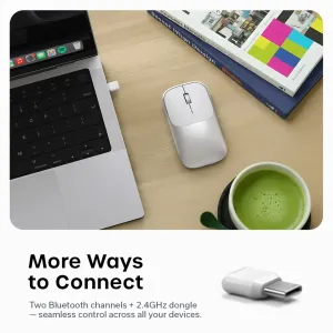 Satechi Slim EX sølvfarget trådløs mus med USB-C-dongel vist på et skrivebord ved siden av en bærbar PC og bøker