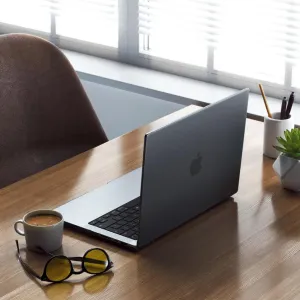 Satechi Eco Hardshell Case på en 14-tommers MacBook Pro, vist åpen på et trebord i et arbeidsområde