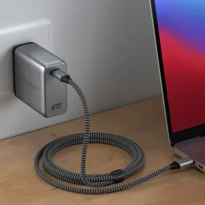 Cargador de pared Satechi de 100 W GaN USB-C PD conectado a una toma de corriente, cargando un portátil con un cable trenzado