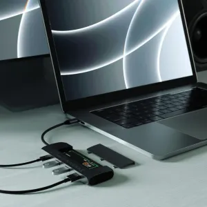 Satechi USB-C-hybridimoniporttisovitin kannettavan tietokoneen vieressä, liitettyine kaapeleineen ja irrotettavan SSD-kelkan suojuksineen.