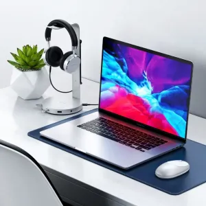 Satechi-alumiinikuuloketeline USB-keskittimellä, jossa on korvan ympärille asettuvat kuulokkeet siistillä työpöydällä kannettavan tietokoneen vieressä.