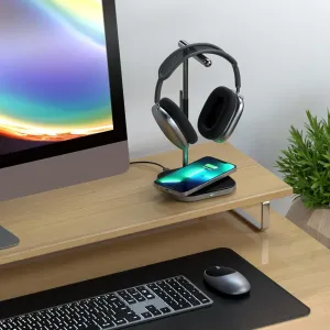 Satechi hodetelefonstativ i aluminium med trådløs ladeplate, som holder over-ear-hodetelefoner på et skrivebord.