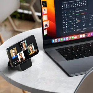 Satechi magnetischer Wallet-Ständer in Schwarz, gefaltet als Smartphone-Ständer neben einem Laptop auf einem Tisch