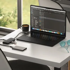 Satechi USB-C-moniporttisovitin liitettynä kannettavaan tietokoneeseen sekä SD- ja microSD-kortteja pöydällä.