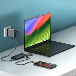 Satechi USB-C-moniporttisovitin liitettynä kannettavaan tietokoneeseen, punottu kaapeli ja puhelin työpöydällä