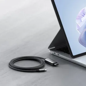 Cable trenzado Satechi de USB-C a HDMI 2.1 con conectores USB-C y HDMI junto a un portátil