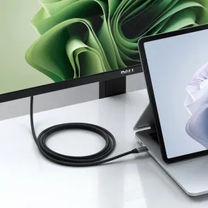 Cable trenzado Satechi USB-C a HDMI 2.1 que conecta un portátil a un monitor Dell sobre un escritorio.