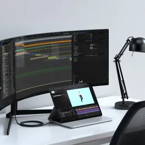 Cable Satechi USB-C a HDMI 2.1 junto a un monitor curvo y una tableta en un espacio de trabajo moderno