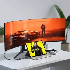 Satechi USB-C–HDMI 2.1 -sovitin liitettynä kannettavaan tietokoneeseen ja kaarevaan näyttöön pelipöytäasetelmassa