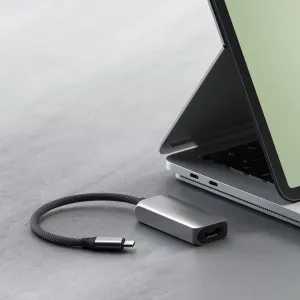 Satechi USB-C–HDMI 2.1 -sovitin, jossa on punottu kaapeli ja HDMI-portti, kannettavan tietokoneen vieressä
