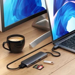 Satechi USB-C-moniporttisovitin liitettynä kannettavaan tietokoneeseen, SD-kortteja ja USB-muistitikku työpöydällä.