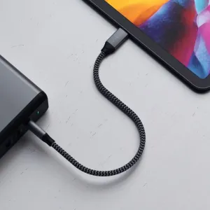 Cable trenzado Satechi de USB-C a USB-C conectado a una tableta y a un dispositivo sobre una mesa blanca