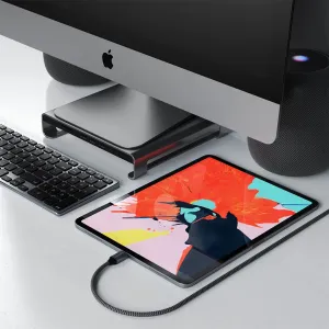 Cable de carga trenzado USB-C a USB-C de Satechi conectado a una tableta sobre un escritorio junto a un iMac