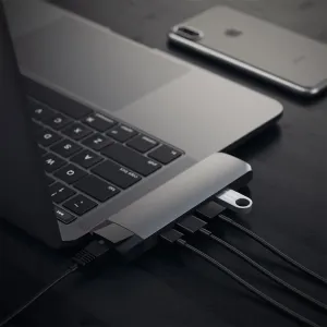 Satechi USB-C Pro Hub kiinnitettynä MacBookiin, ja siihen on liitetty kaapeleita kannettavan porttien laajentamiseksi.