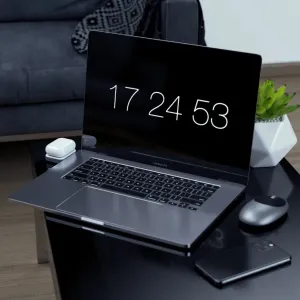 Base de carga inalámbrica Satechi para AirPods junto a un MacBook Pro sobre un escritorio, con un estuche de carga blanco