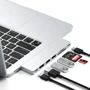 Satechi USB-C Pro Hub Slim, prijungtas prie sidabrinio MacBook, šalia – SD kortelės, USB atmintinės ir kabeliai