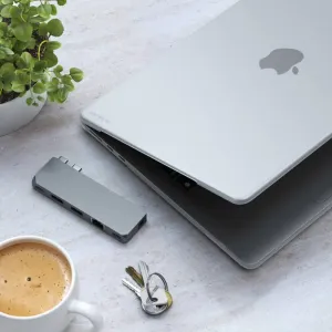 Satechi-etui til MacBook Air M2 vist på en lukket bærbar datamaskin med en kompakt hub på et minimalistisk skrivebord.