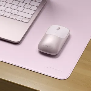 Satechi Form Desk Mat i pudderrosa med syede kanter, vist med en matchende mus og bærbar computer på et skrivebord i træ.