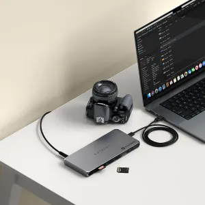 Satechi Thunderbolt 4 -telakointiasema, jossa on useita portteja, liitettynä pöydällä olevaan kannettavaan tietokoneeseen