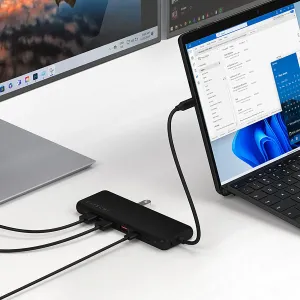 Satechi 13 viename USB-C kelių jungčių adapteris, keliais kabeliais prijungtas prie nešiojamojo kompiuterio ant stalo