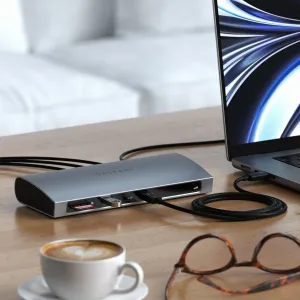 Satechi Thunderbolt 4 -telakka, jossa on liitetyt kaapelit, USB-portit ja SD-korttipaikka kannettavan tietokoneen vieressä