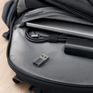 Satechi USB-A–USB-C-sovitin avaruusharmaana kannettavan tietokoneen vieressä avoimessa repussa.