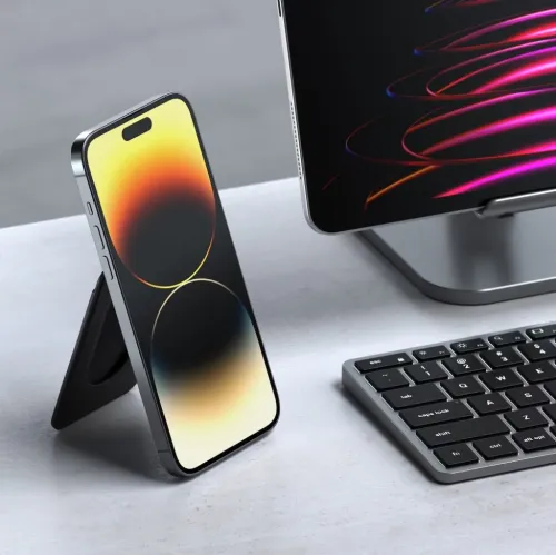 Juodos spalvos piniginės stovas, sulankstytas į trikampę atramą už portretiniu režimu ant stalo padėto "iPhone", su lygia priekine plona forma