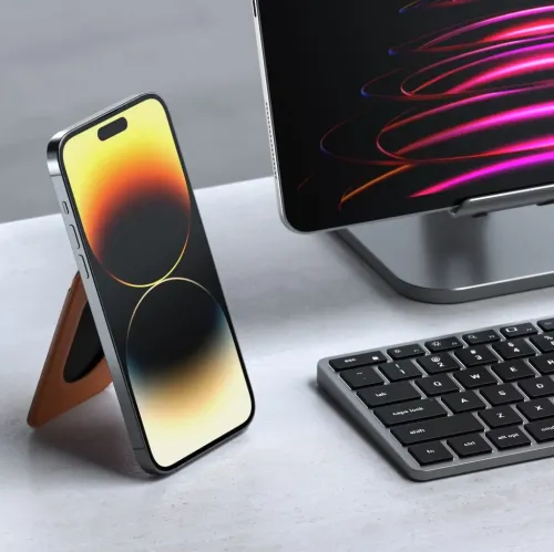 Magnetisk pungstativ i brunt vegansk læder, foldet til en trekantet støtte bag en iPhone på bordet ved siden af tastaturet.