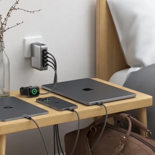 Satechi USB-C-reiseladeren med fire porter sitter i stikkontakten, og de flettede kablene lader laptop, nettbrett og klokke.