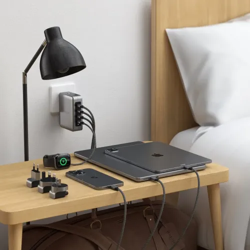 Satechi 4-Port-USB-C-GaN-Reiseladegerät, das neben einem Bett ein Tablet, ein Smartphone und eine Uhr mit Strom versorgt