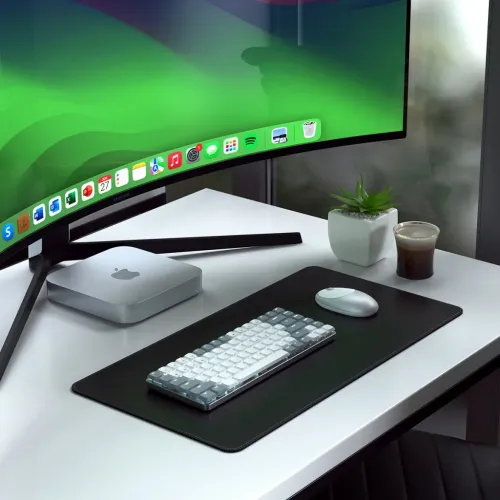 Satechi Slim lysegråt mekanisk tastatur med lav profil på sort skrivebordsmåtte, ved siden af musen, foran den buede skærm.