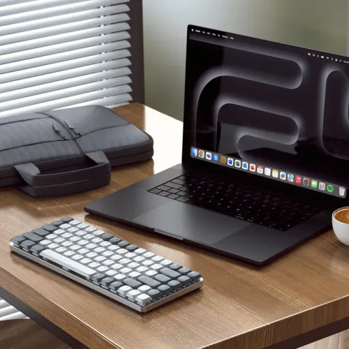 Satechi Slim mekanisk tastatur i lysegrå, kompakt lavprofil med tofarvede afrundede taster, der ligger på skrivebordet.