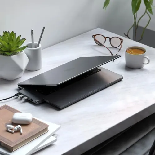 Hardshell-etui for MacBook Pro 14 synlig på en delvis åpen, mørk bærbar datamaskin på skrivebordet, med synlige porter og tynn profil.