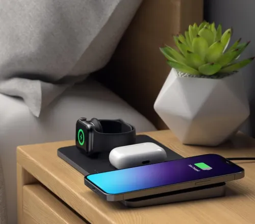 Satechi Trio svart trådlös laddningsplatta på nattduksbord, med telefon, klocka och hörlursfodral på ytan samt ansluten kabel.