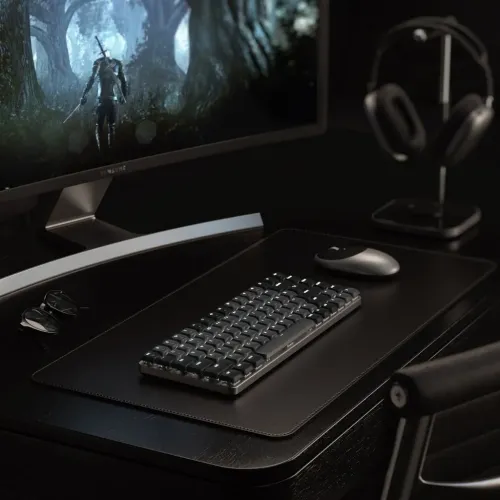 Satechi SM1 Slim tangentbord i mörkgrått med vit bakbelysning på skrivbordsunderlägg, bredvid mus och framför böjd skärm.