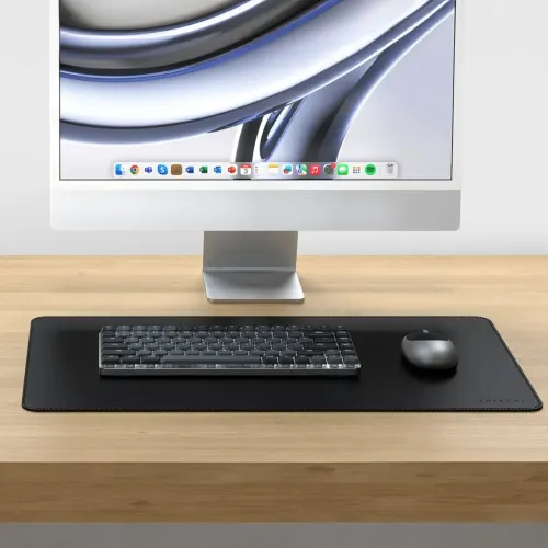Satechi SM1 mörkgrått mekaniskt tangentbord med låg profil på svart skrivbordsunderlägg, bredvid grå mus och framför skärm.