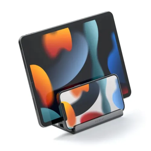 Dubbelfackat stativ håller en surfplatta stående och en smartphone liggande i främre spåret; mörkgrå bas med SATECHI-logga.