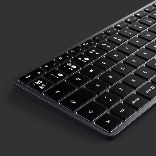 Tangentbord med låg profil och bakgrundsbelysta svarta tangenter, svart aluminiumram och sned närbild av högra nedre hörnet.