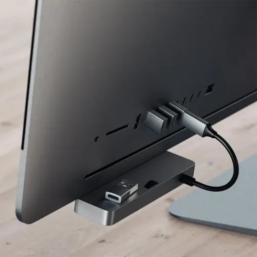Space gray USB-A to USB-C adapter plugs into your computer's rear USB-A port; compact metal profile, another one is on the stand below.