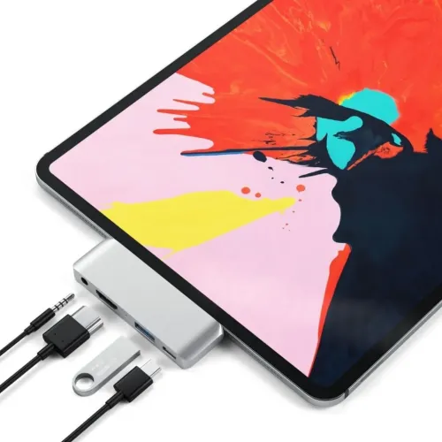 Satechi USB-C Mobile Pro Hub i sølv på iPad, med porte til HDMI, USB-A og 3,5 mm, samt kabler og USB-hukommelsesnøgle ved siden af.
