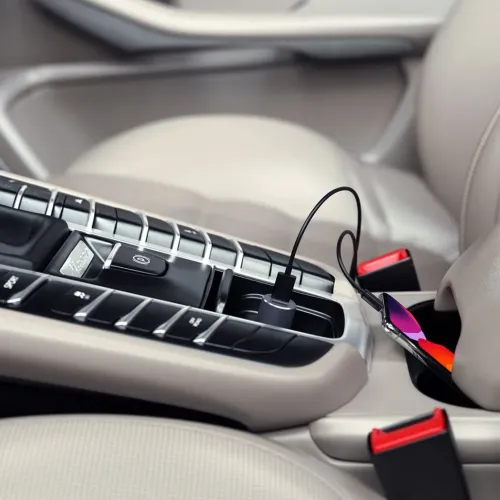 Satechi space grey billader i strømuttaket på bilens midtkonsoll, sylindrisk form, med kabel til smarttelefon i koppholderen.