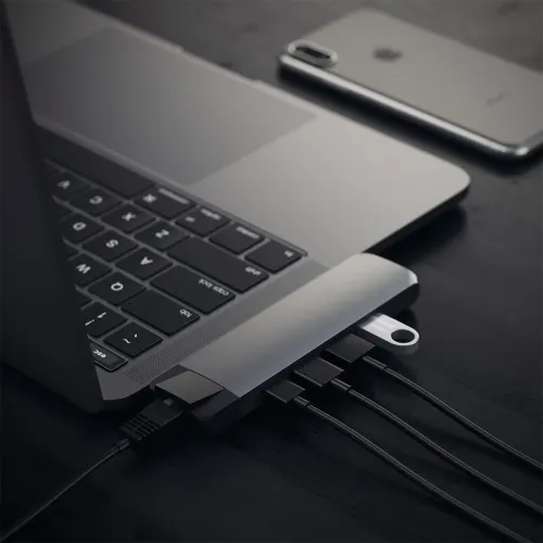 Erdviai pilkos spalvos "USB-C Pro" koncentratorius, prijungtas prie "MacBook", su įjungtu eterneto kabeliu, keliais USB-C kabeliais ir maža USB atmintine.