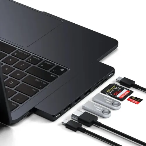 Satechi USB-C-hubb ansluten till en MacBook, med USB-C-, SD- och microSD-portar samt lagringstillbehör i närheten