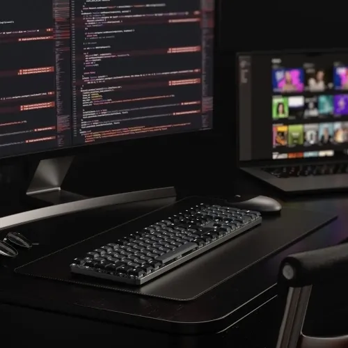 Satechi SM3 plāna mehāniskā aizmugurgaismota tastatūra uz tumša darbstacijas galda ar kodu monitoros