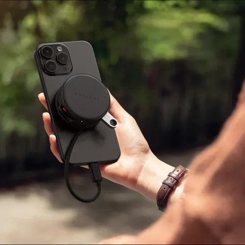 Satechi OntheGo 7-i-1 multiportadapter tilsluttet en smartphone med USB-C-kabel i hånden udendørs