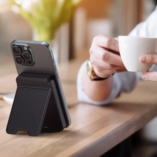 Satechi OntheGo Qi2 magnetisk powerbankstativ som holder en smarttelefon oppreist på et trebord.